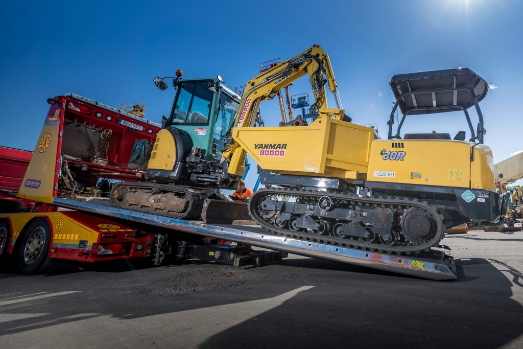 Flakbärgare från Assistancekåren transporterar en grävmaskin