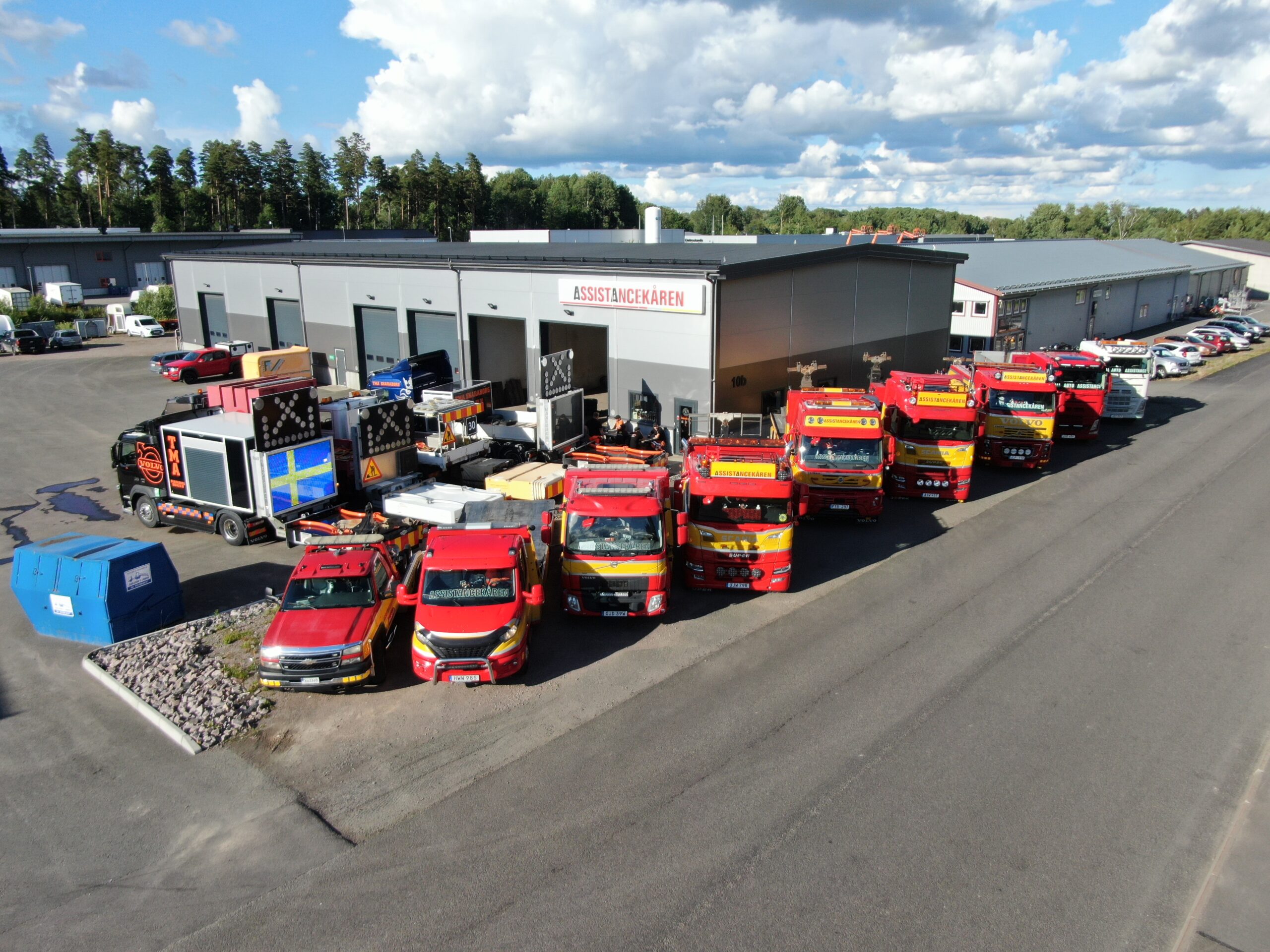 Assistancekårens station i Skövde med flera bärgningsfordon uppställda framför byggnaden under en solig dag.