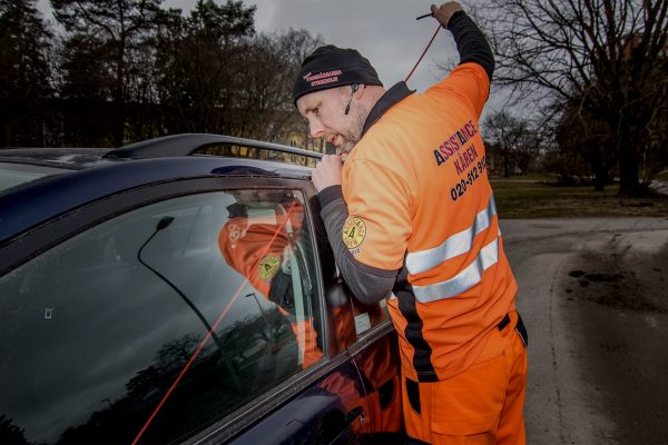 Assistancekåren bärgare på ett vägassistansuppdrag. Han öppnar en bildörr på en svart personbil till en förare som tappat sin bilnyckel intill en park